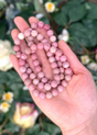 Hand holding pink beads with a blurred natural background